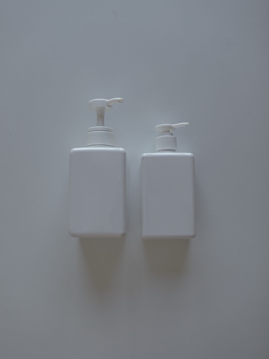 Two plain white unlabeled plastic pump bottles on a light gray background
